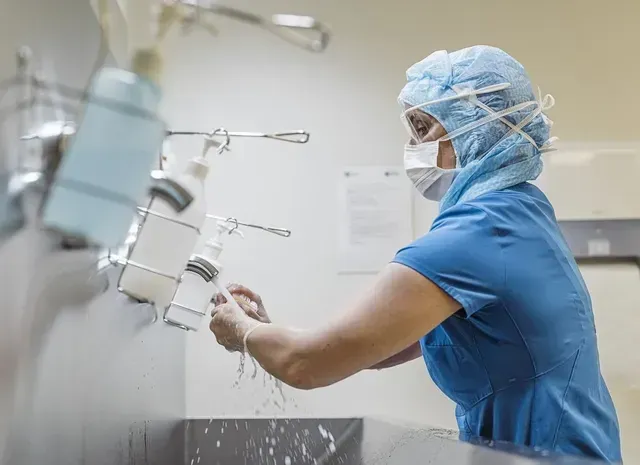 a surgeon is washing her hands in a hospital sink .
