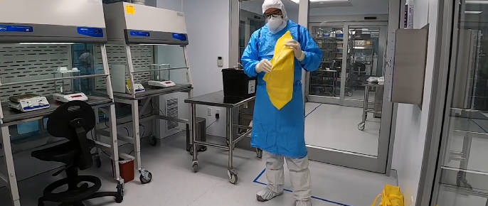 a man in a lab coat and mask is holding a yellow cloth .