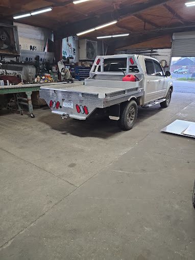 A truck with a flat bed is parked in a garage.