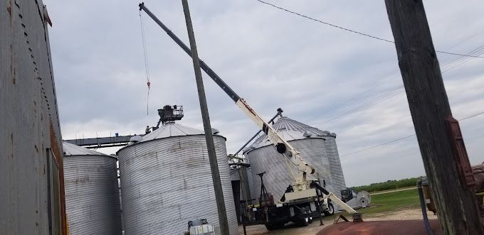 A crane is being used to lift a roof of a silo.
