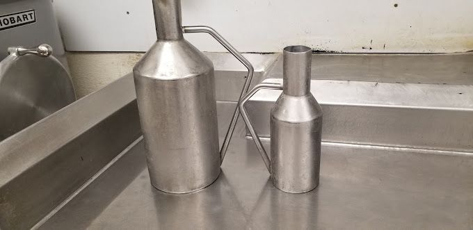 Two stainless steel containers are sitting on a stainless steel counter.