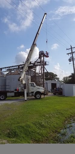 A truck with a crane attached to it is parked in a grassy field.