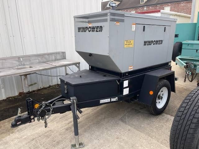 A trailer with a generator on it is parked in front of a building.