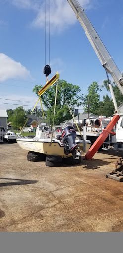 A boat is being lifted by a crane in a parking lot.