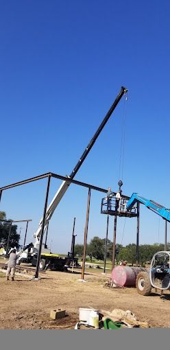 A crane is being used to lift a metal structure in a field.
