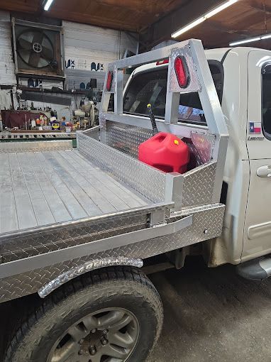 A white truck with a red gas can in the bed is parked in a garage.