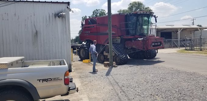 A man is standing next to a tractor in a parking lot.