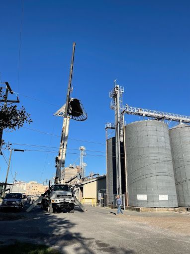A truck with a crane attached to it is parked in front of a large building.
