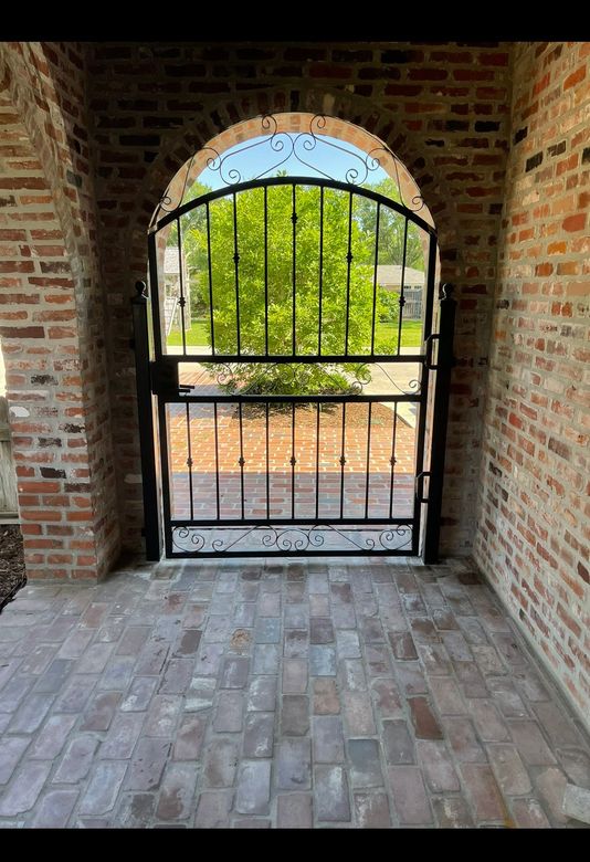 There is a gate in the middle of a brick wall.