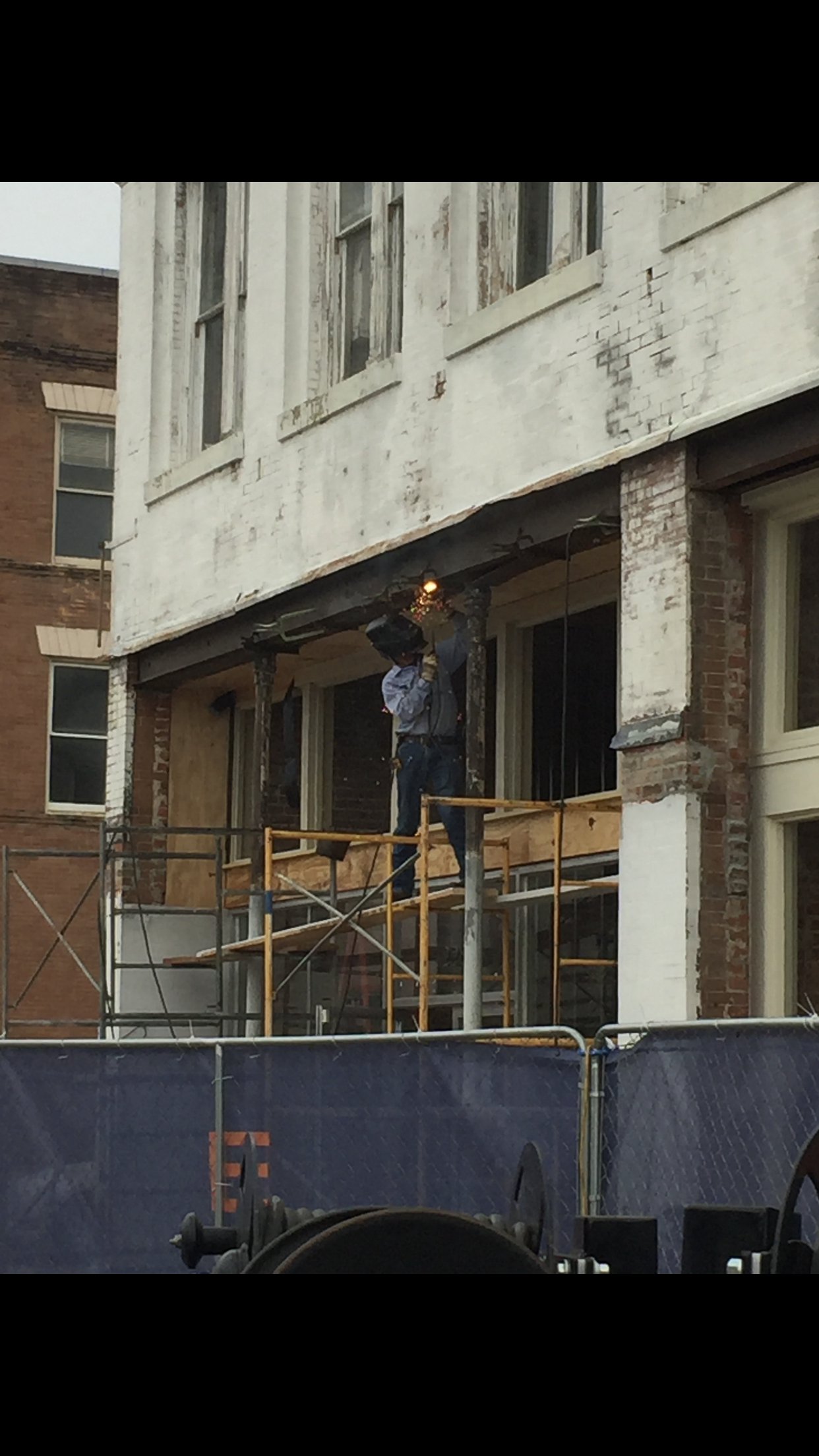 A man is welding on the side of a building