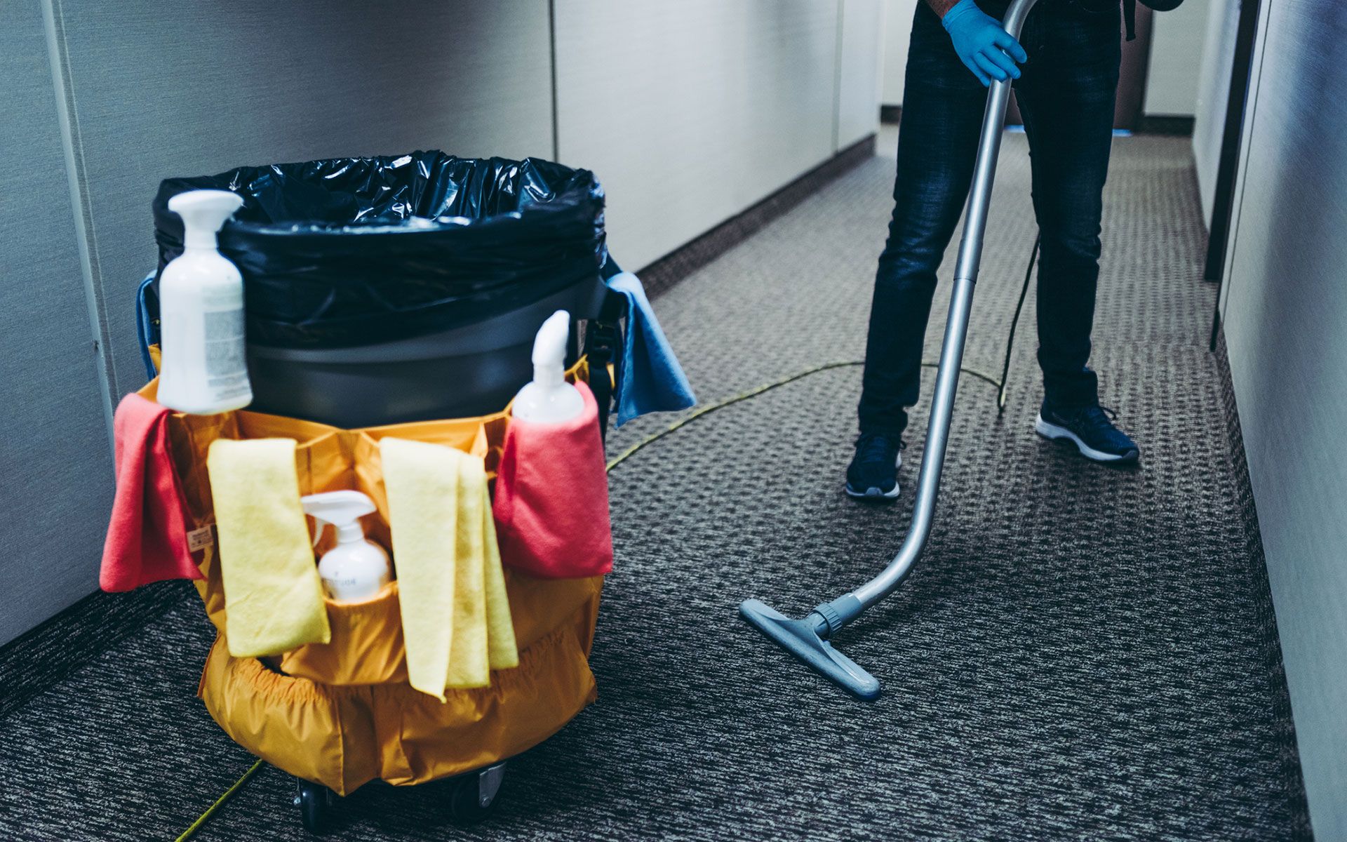 A man is cleaning a hallway with a vacuum cleaner.