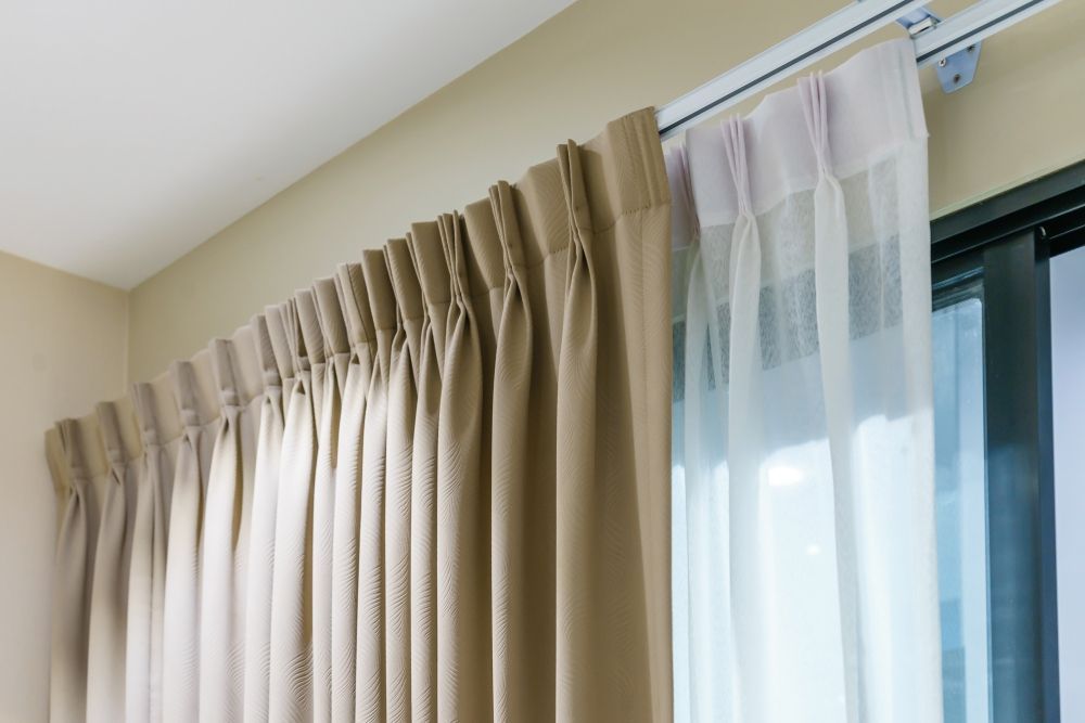Beige pleated curtains beside a sheer white curtain on a window with daylight. — Another Blind Man in Tewantin, QLD