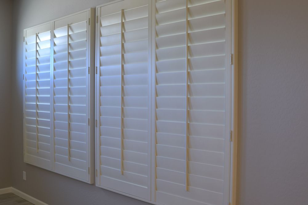 White Plantation Shutters Covering Three Tall Windows on a Beige Wall — Another Blind Man in Kawana Waters, QLD