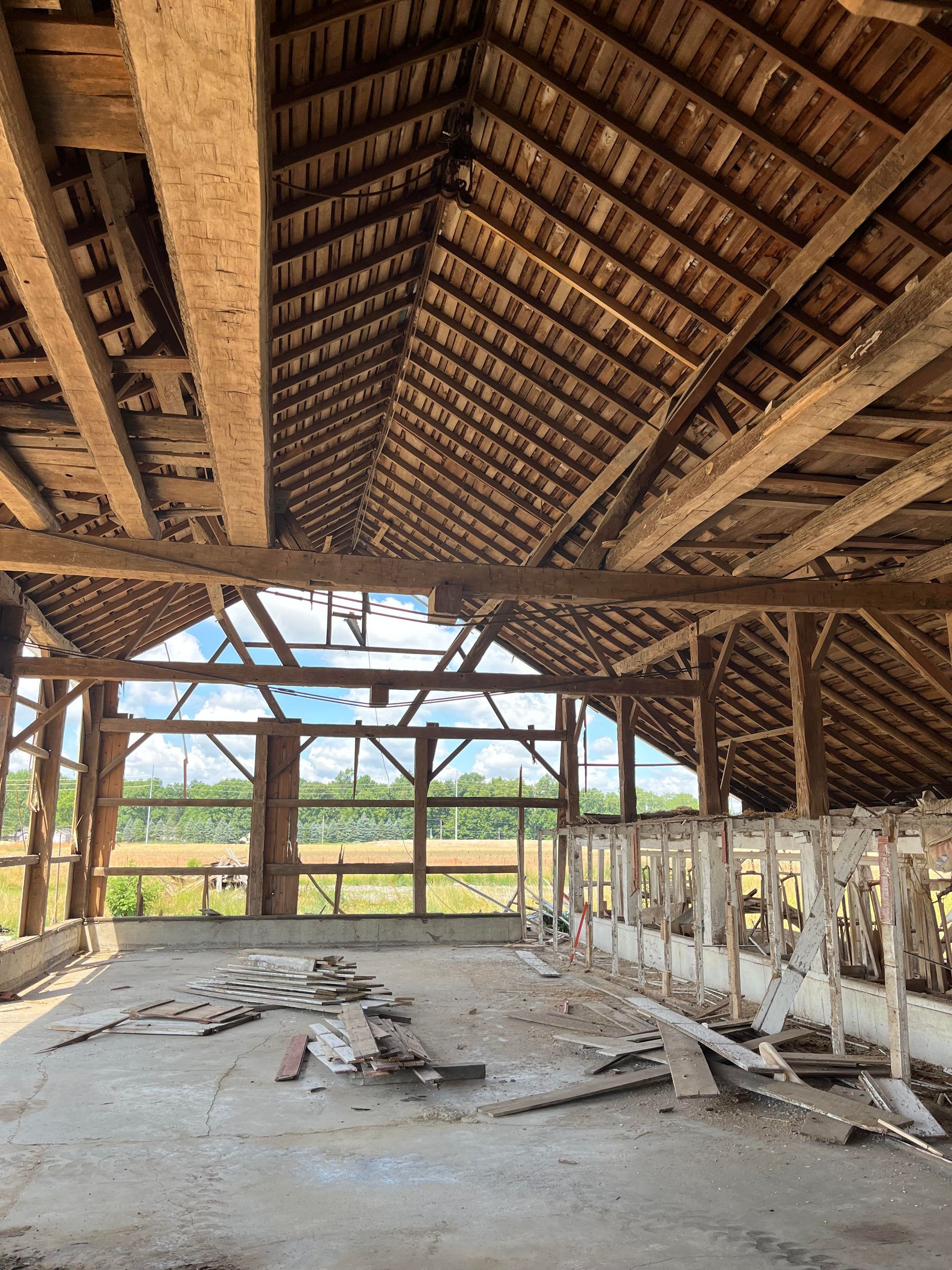 Rustic barn interior with exposed beams, stalls, and a concrete floor showing how to convert a barn cheaply.