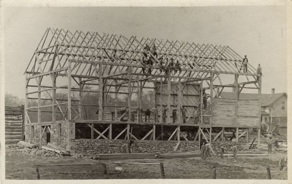 Workers constructing historic timber frames for a barn.