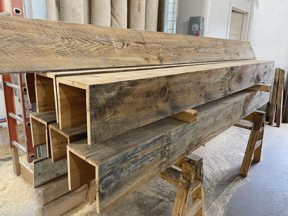 Rustic reclaimed hand-hewn beams stacked on sawhorses.