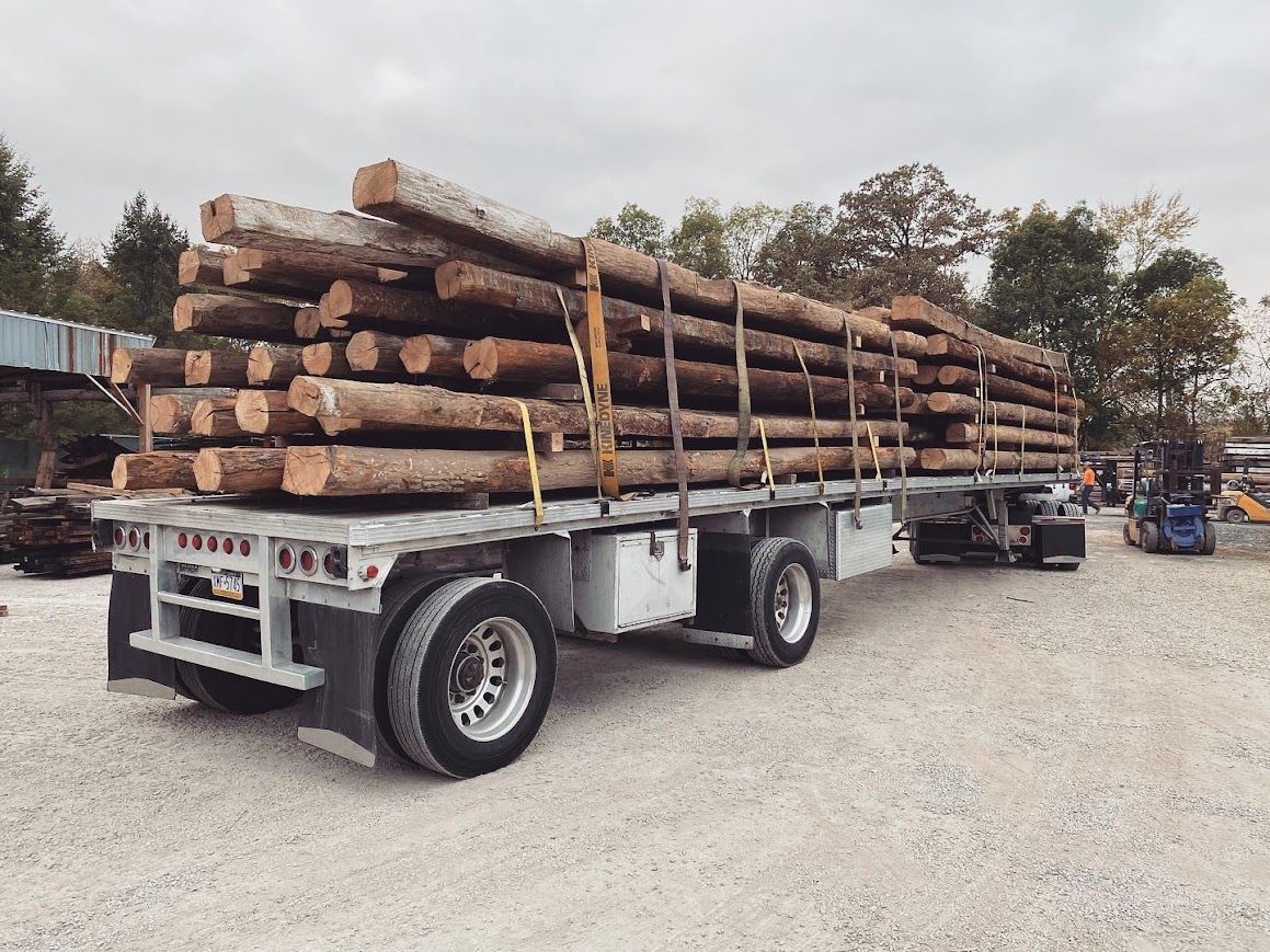 Flatbed trailer with logs from historic barn frame suppliers.