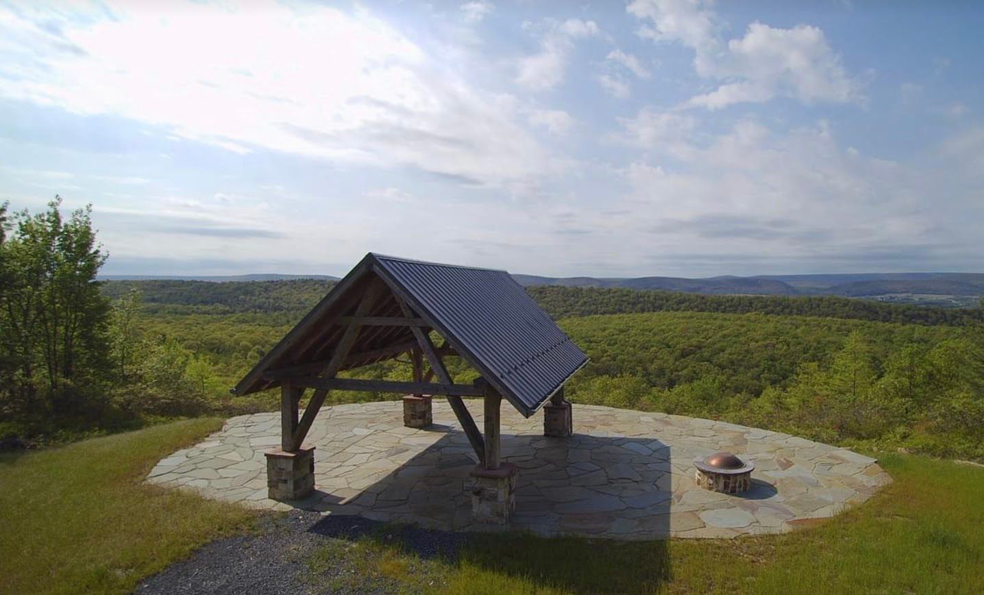 Wooden pavilion with custom barn frame design on stone platform.