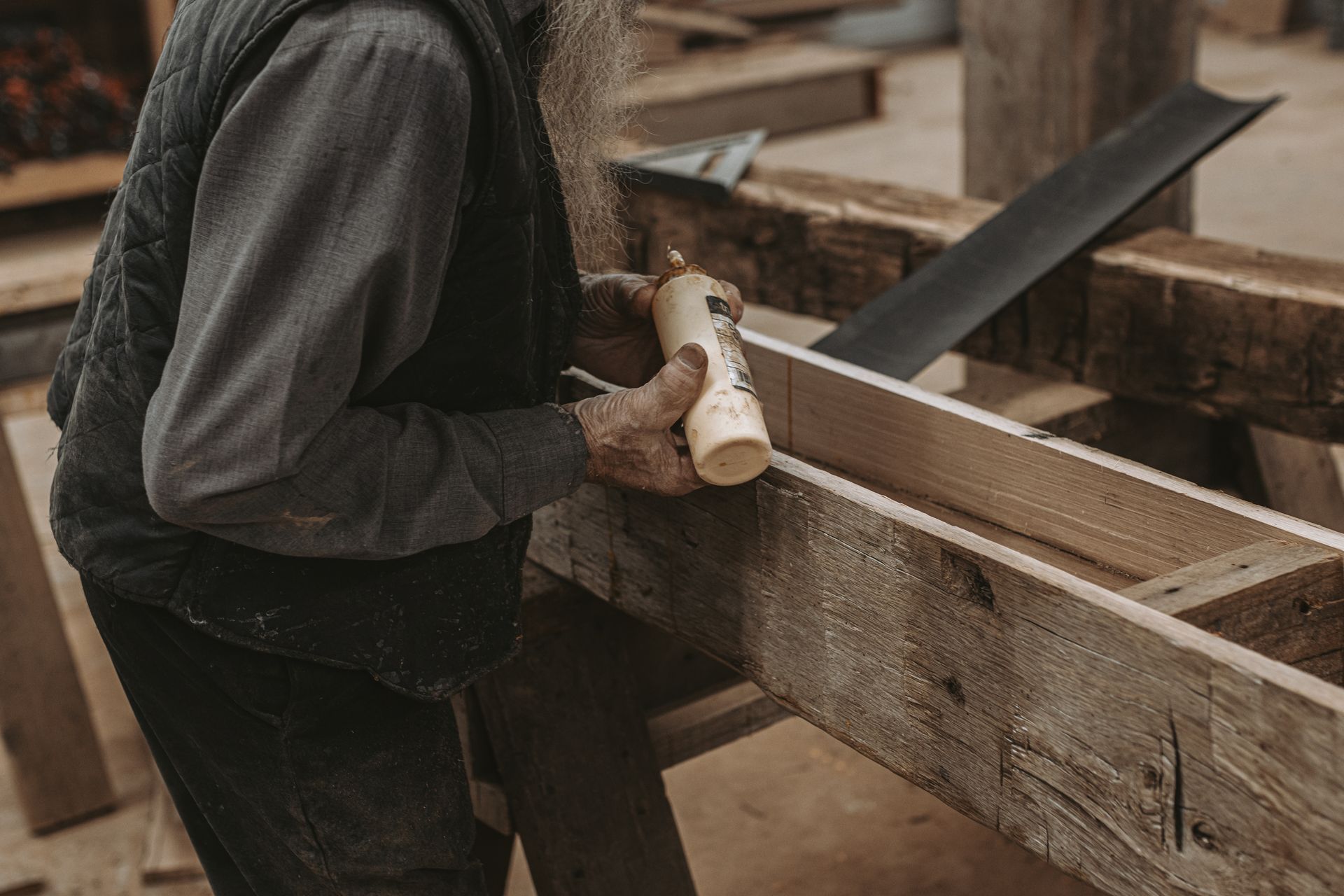 Craftsman applying wood glue to a wooden beam.