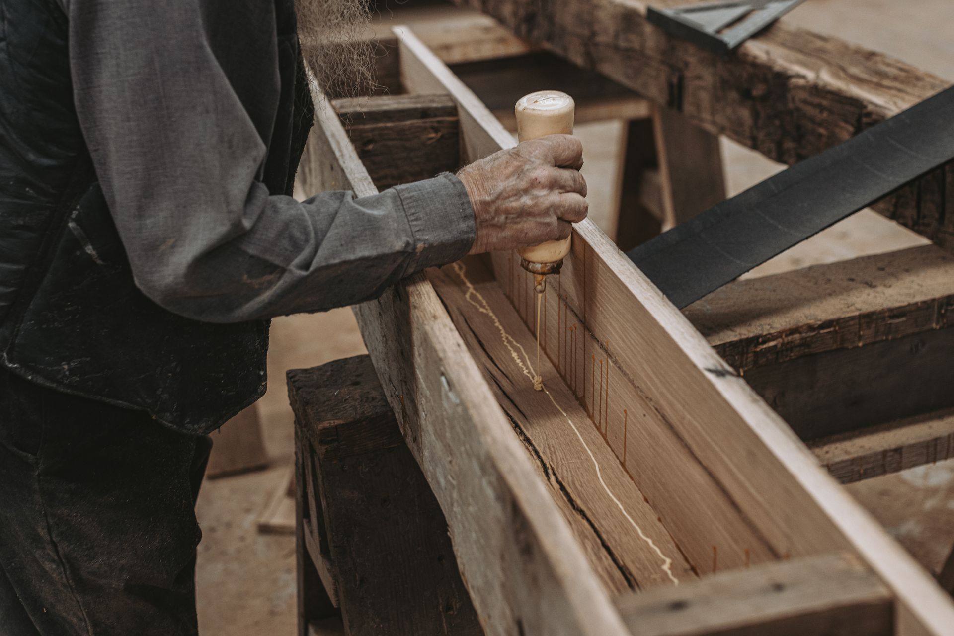 Applying glue to timber in Pennsylvania for woodworking fasteners to ensure strong rustic joints.