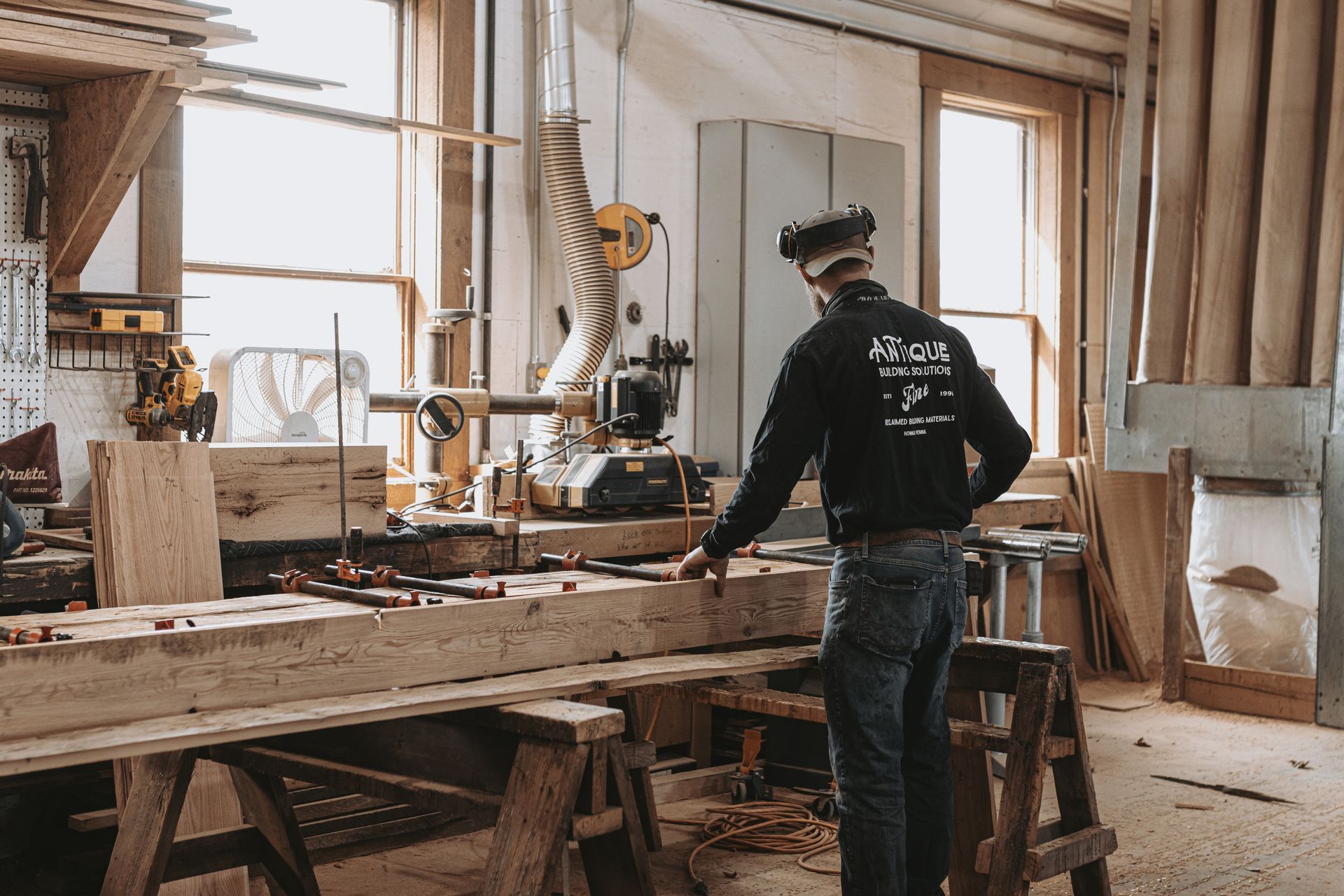 A man is working on a piece of wood in a woodworking shop.