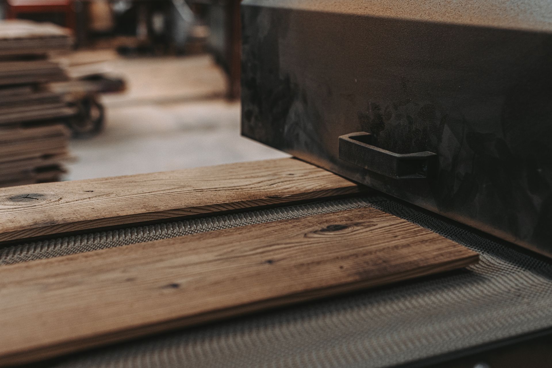 Plain sawn boards on a conveyor in a workshop.