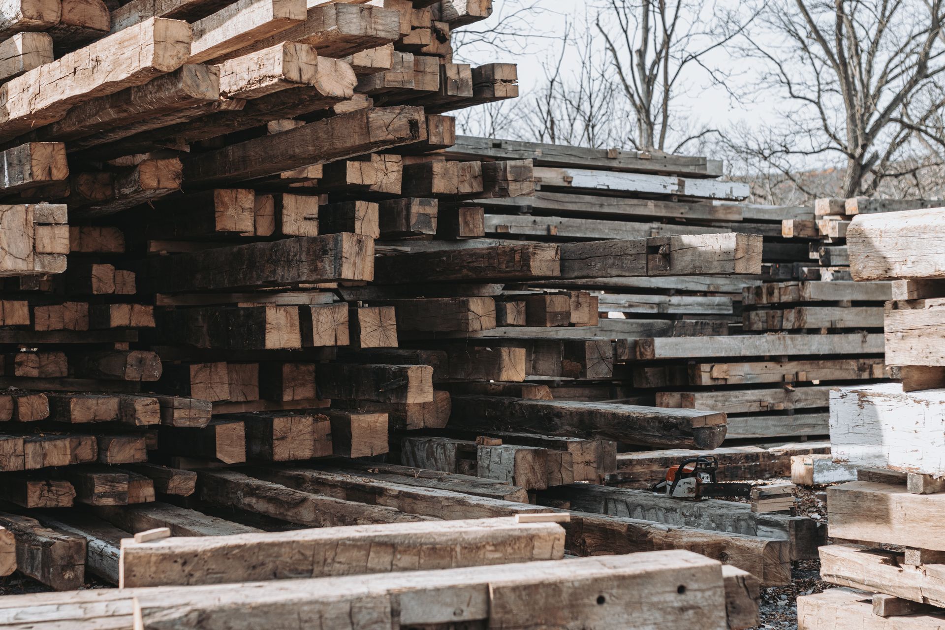 Stack of weathered wooden beams and planks under cloudy skies, showcasing s.