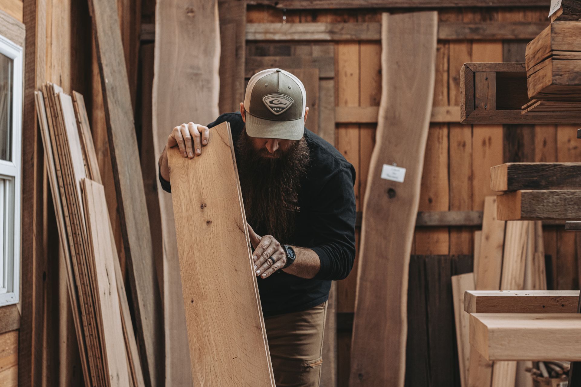 Craftsman inspecting a slab for wood warping in workshop.