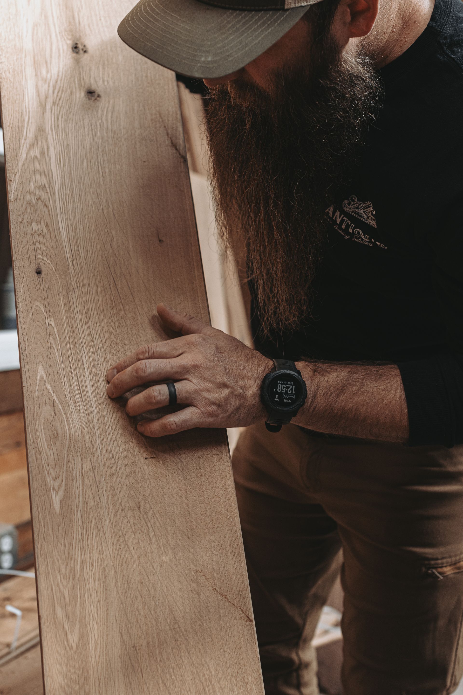 Craftsman inspecting flat grain lumber in a workshop.