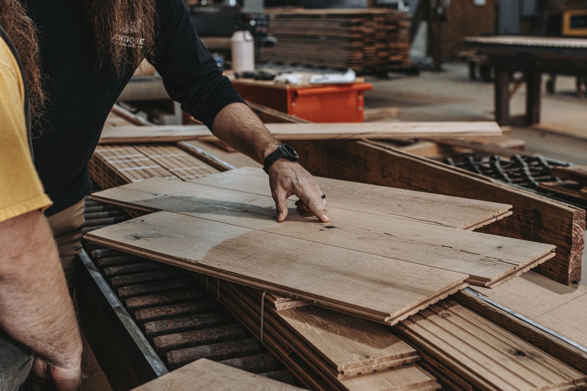 A man is pointing at a piece of wood in a factory.