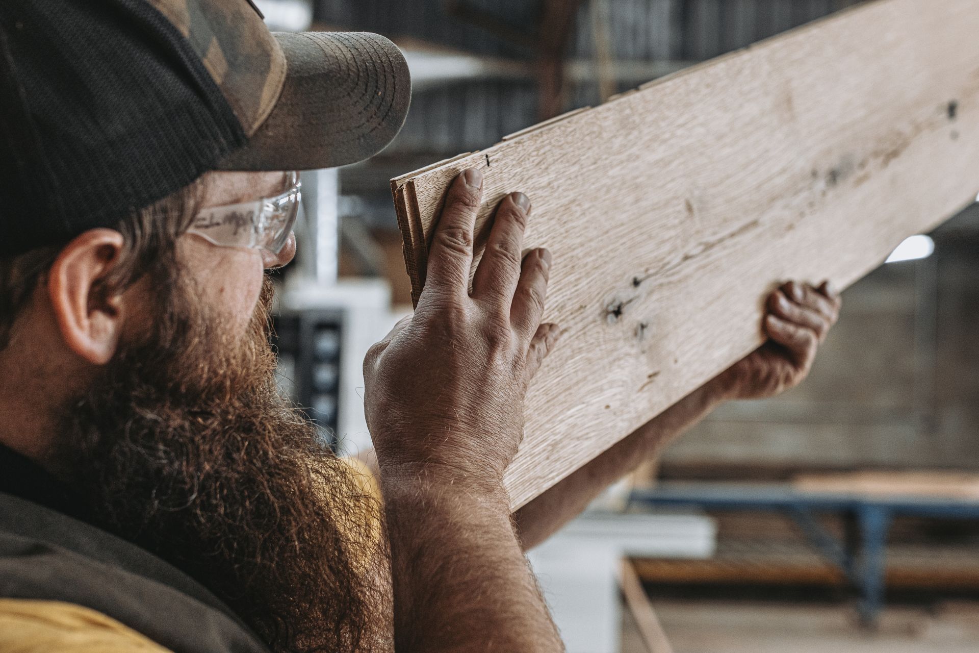 A craftsman inspects a piece of aged wood in a workshop, part of timber frame craftsmanship techniques.