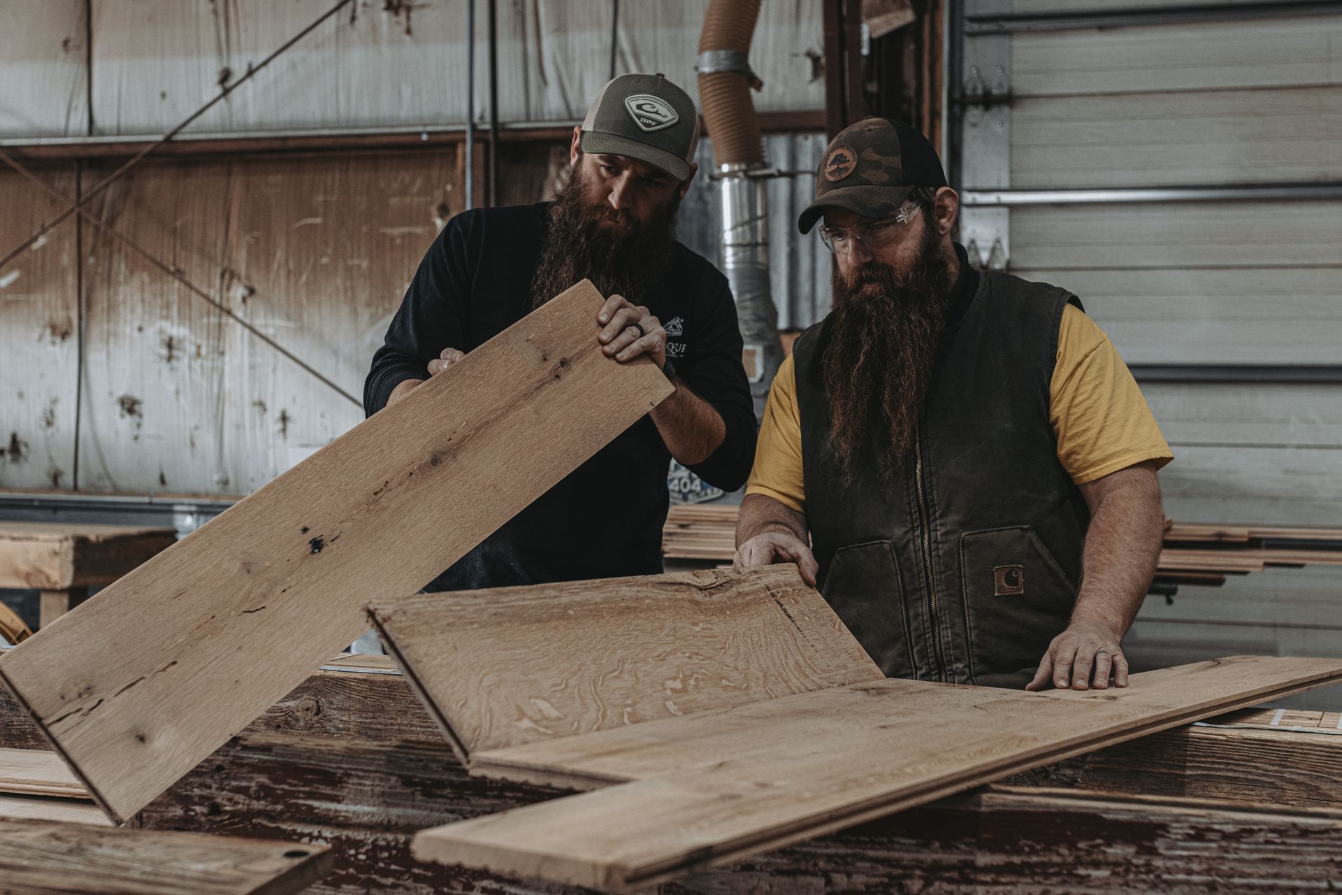 Two woodworkers inspecting reclaimed wood planks in a workshop