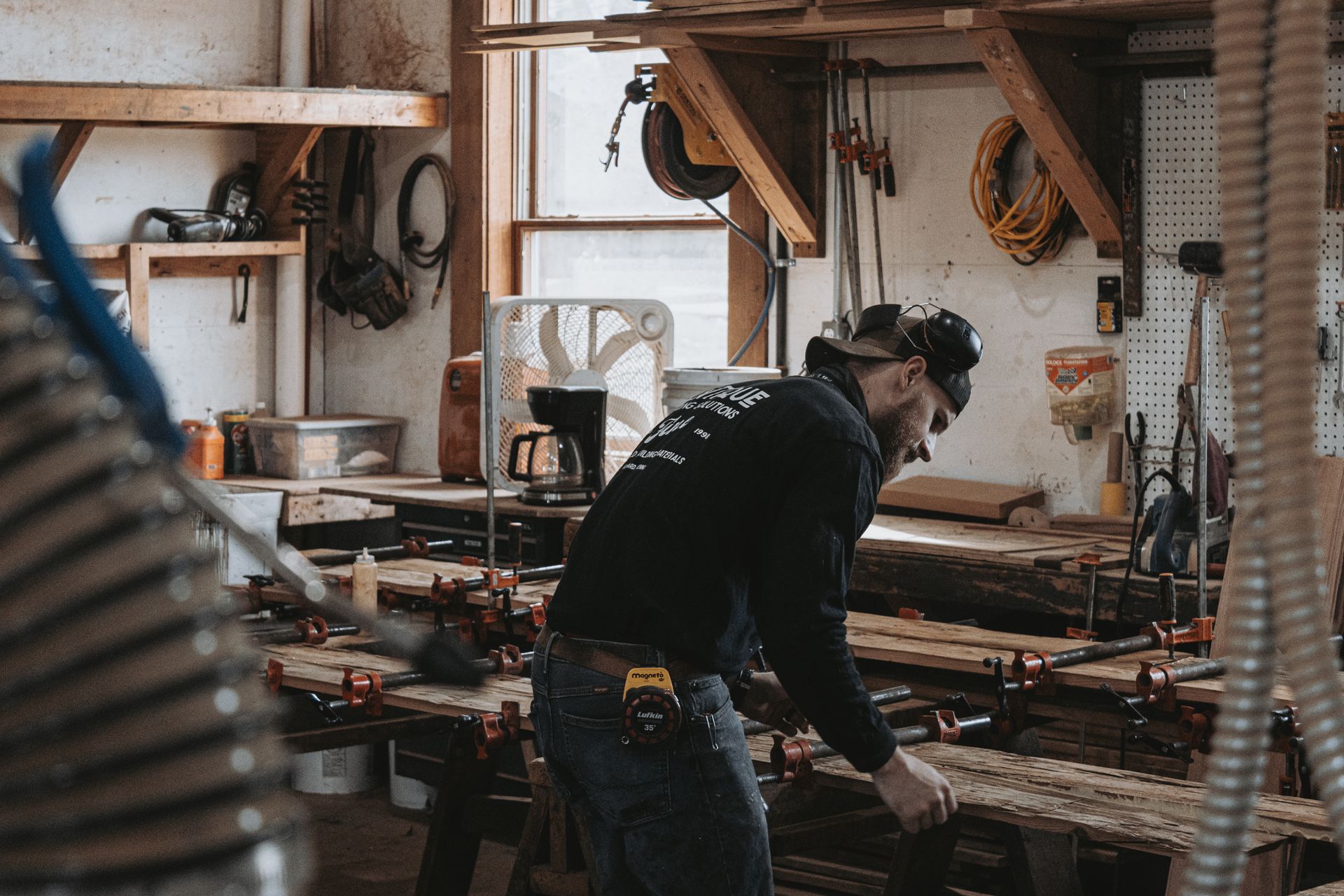 A woodworker in a workshop focused on the repair of barn frames.
