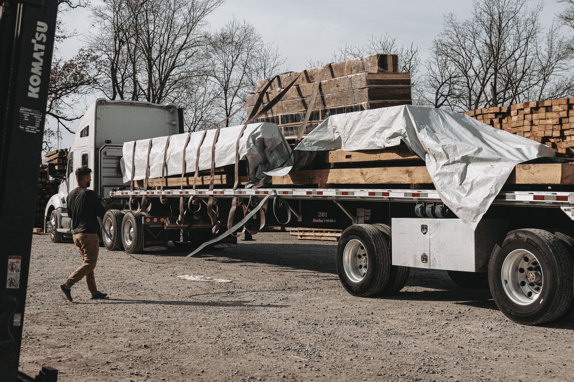 Flatbed truck with beams in a lumberyard, which is part of an Antique barn dismantling service.