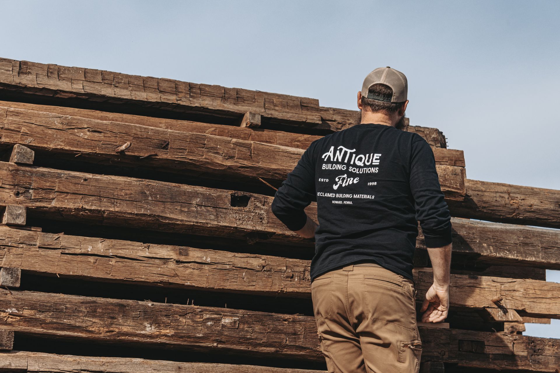 Worker stacking reclaimed timber beams on a Pennsylvania job site