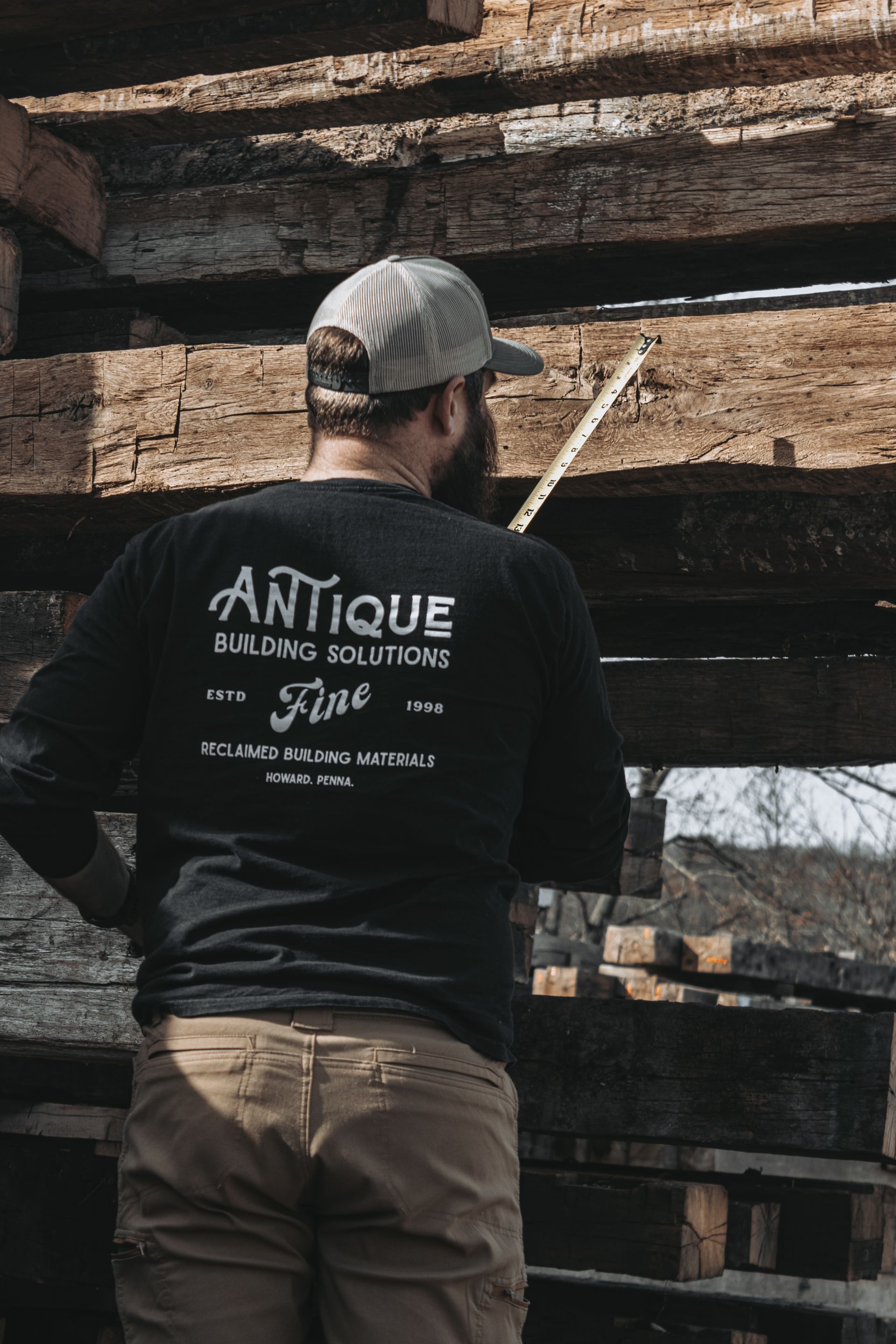 Worker measuring reclaimed beams for antique building solutions.