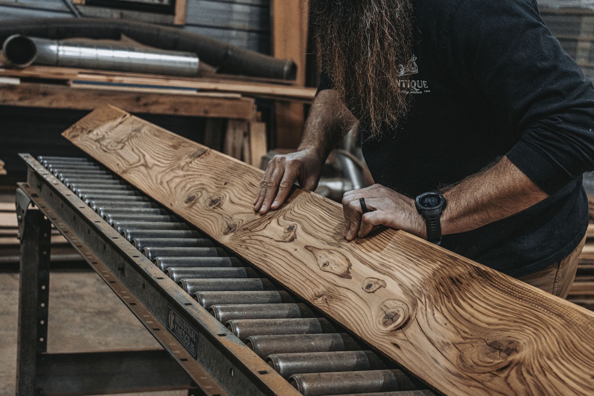 A man is hammering a piece of wood on a conveyor belt.