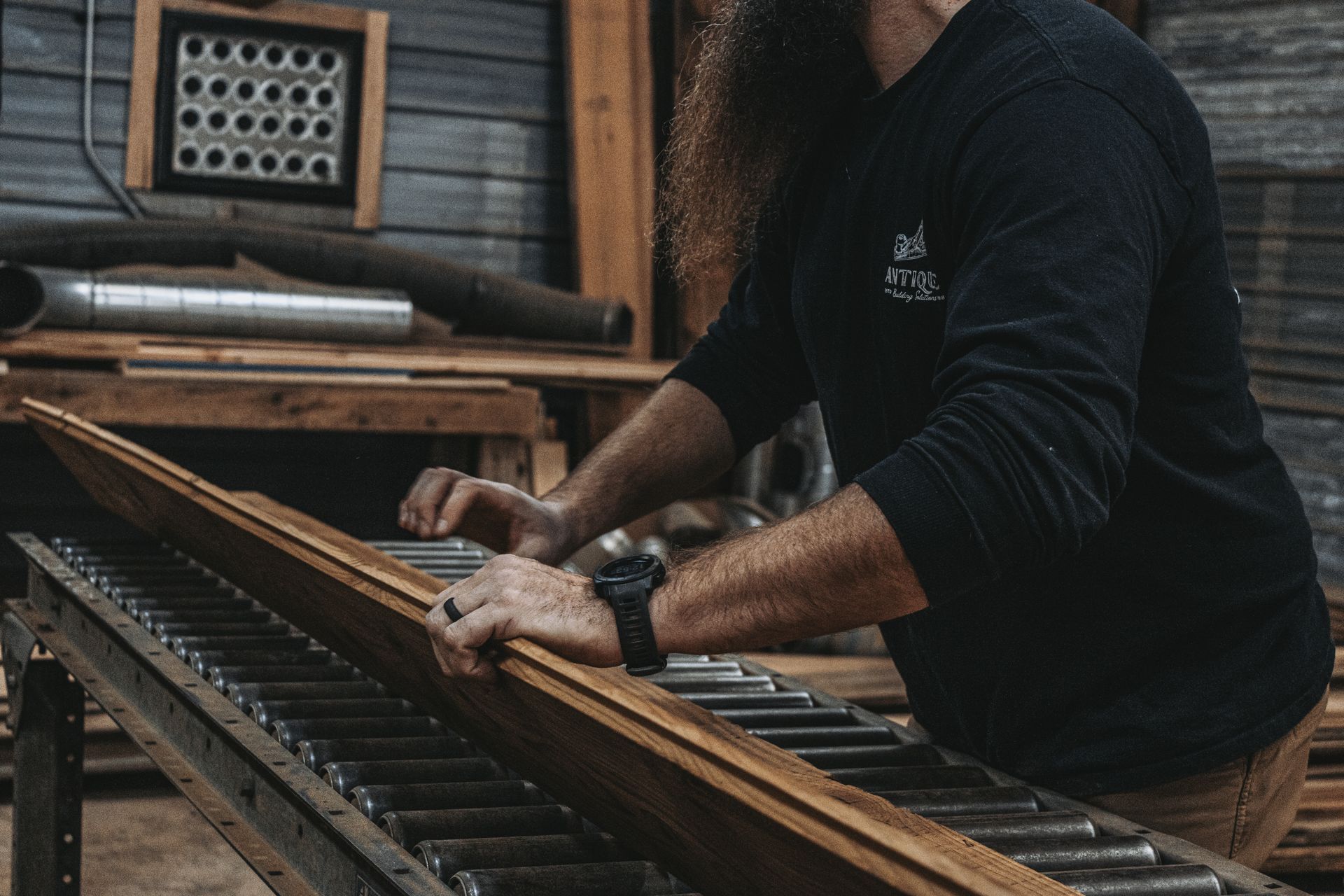 A woodworker repairing a historic barn plank in a workshop.