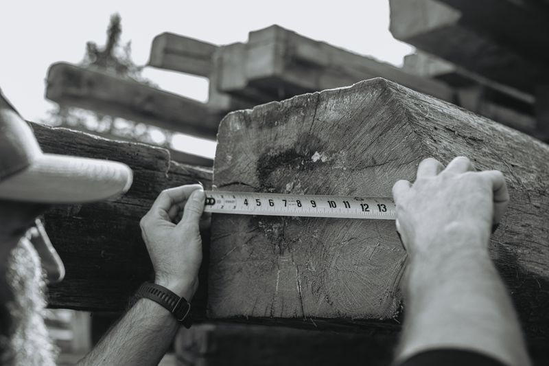 Measuring wooden beam for timber frame reassembly.