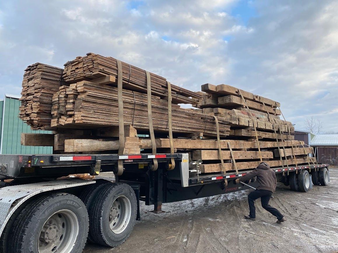 Flatbed trailer loaded with antique barn frame delivery.