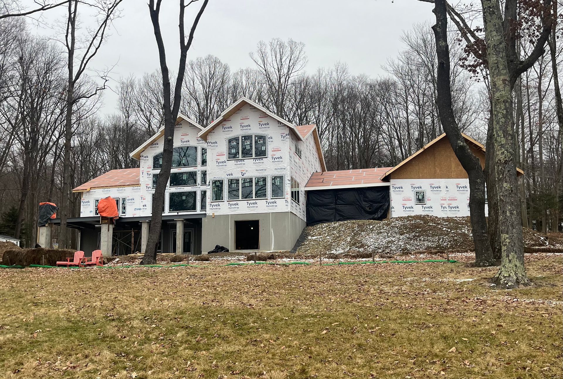 A large house is being built in the middle of a field surrounded by trees.