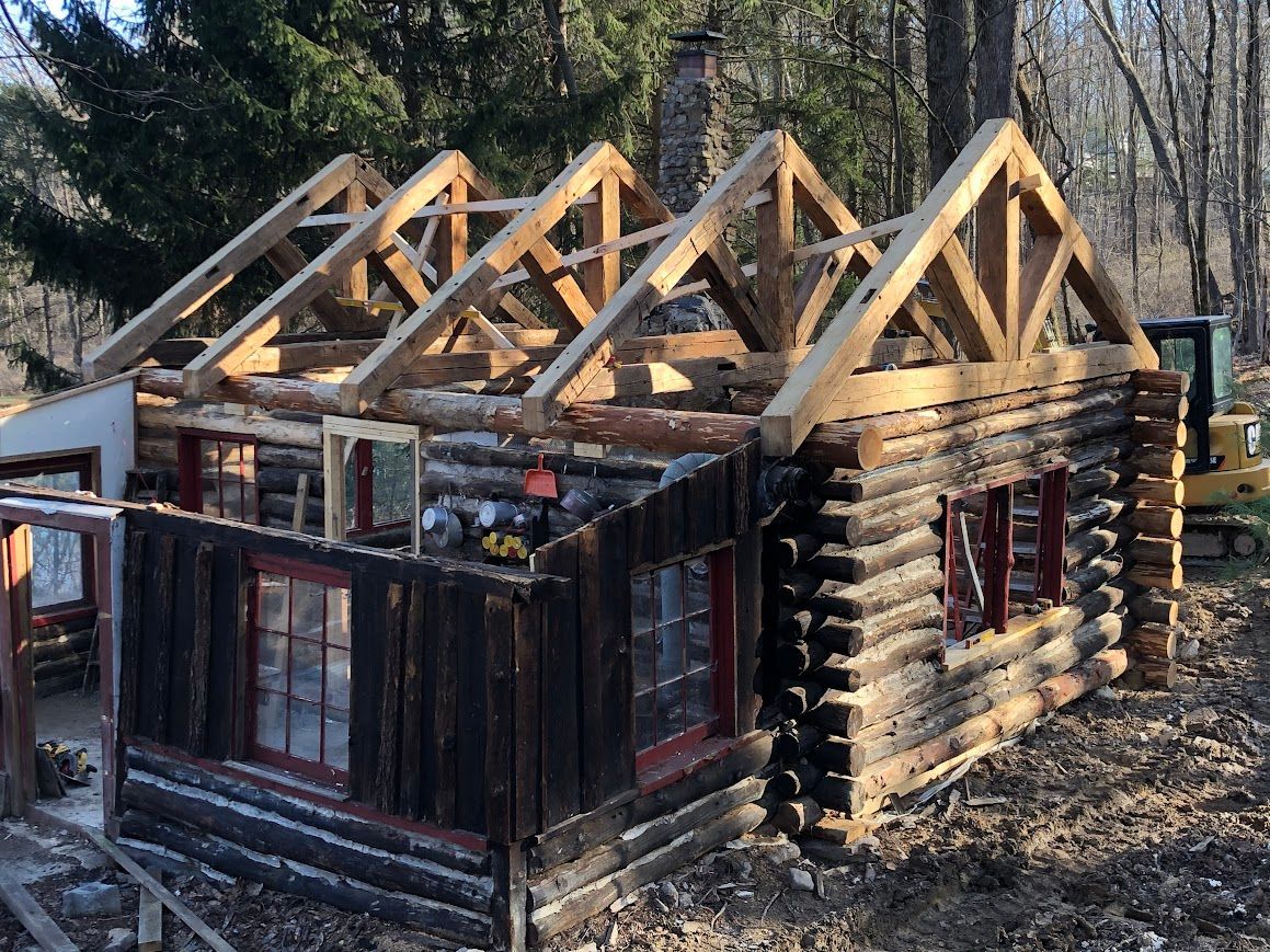 Partially constructed log cabin with custom barn frame design.