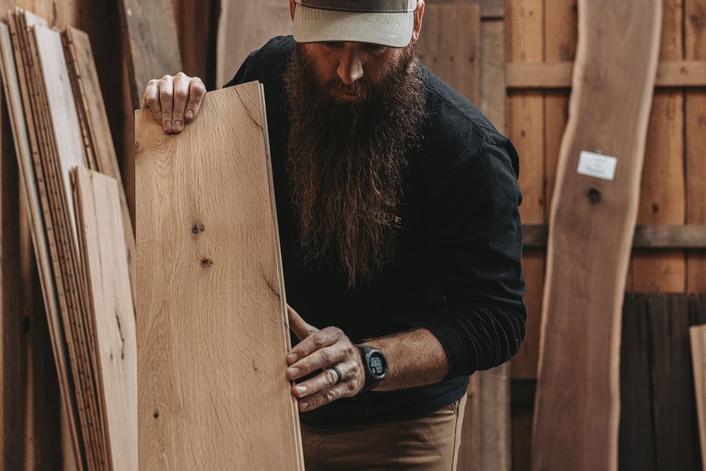 Craftsman Inspecting a Plank of Heritage Reclaimed Wood in Pennsylvania