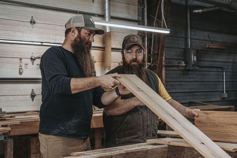 Two craftsmen inspecting wood for barn frame reconstruction.