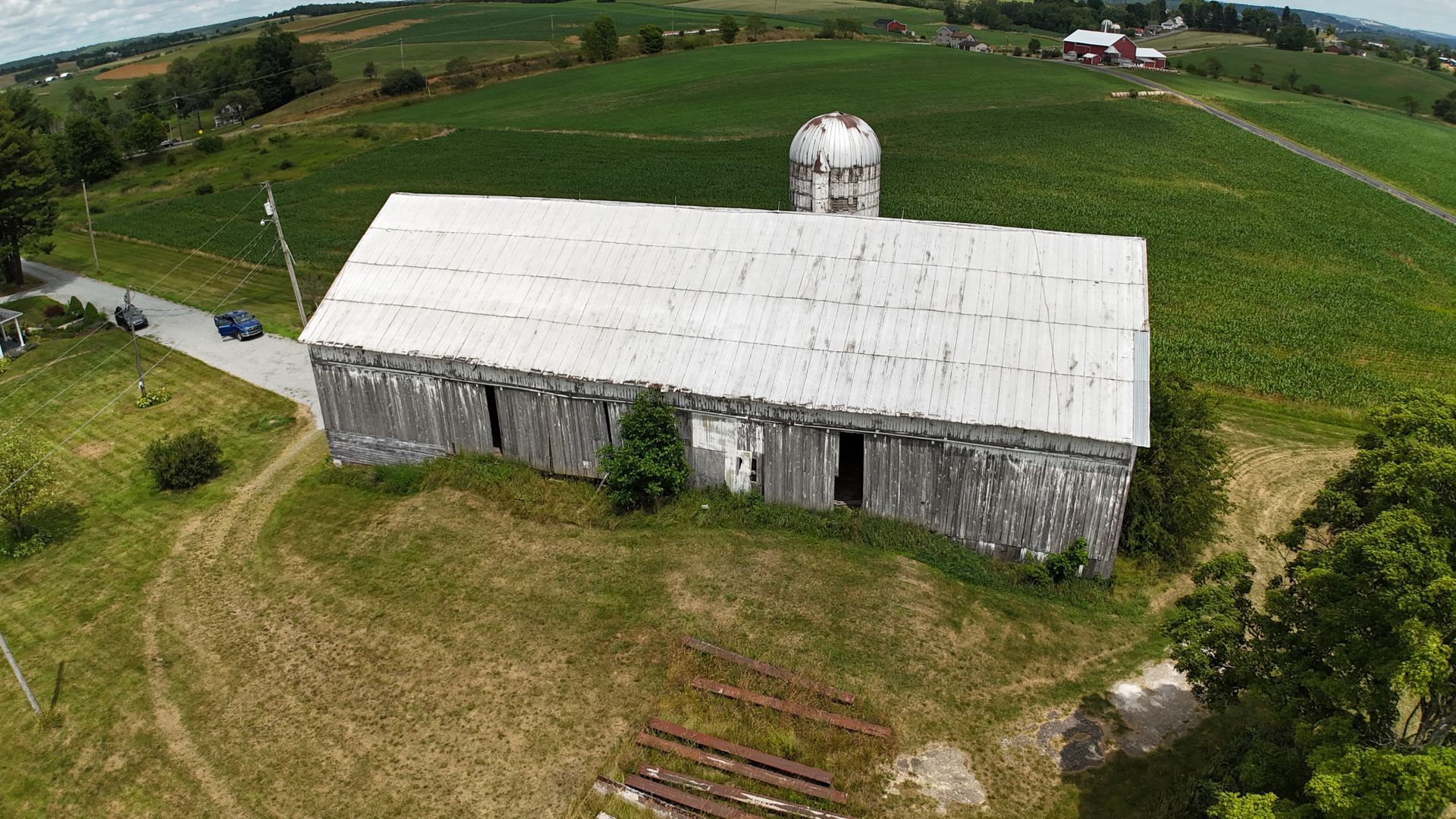 Aerial shot of Pennsylvania farmland with a rustic barn, classic silo, and wide green fields.
