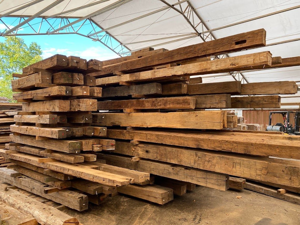 Stacked wooden beams under canopy during historic barn dry-in phase.