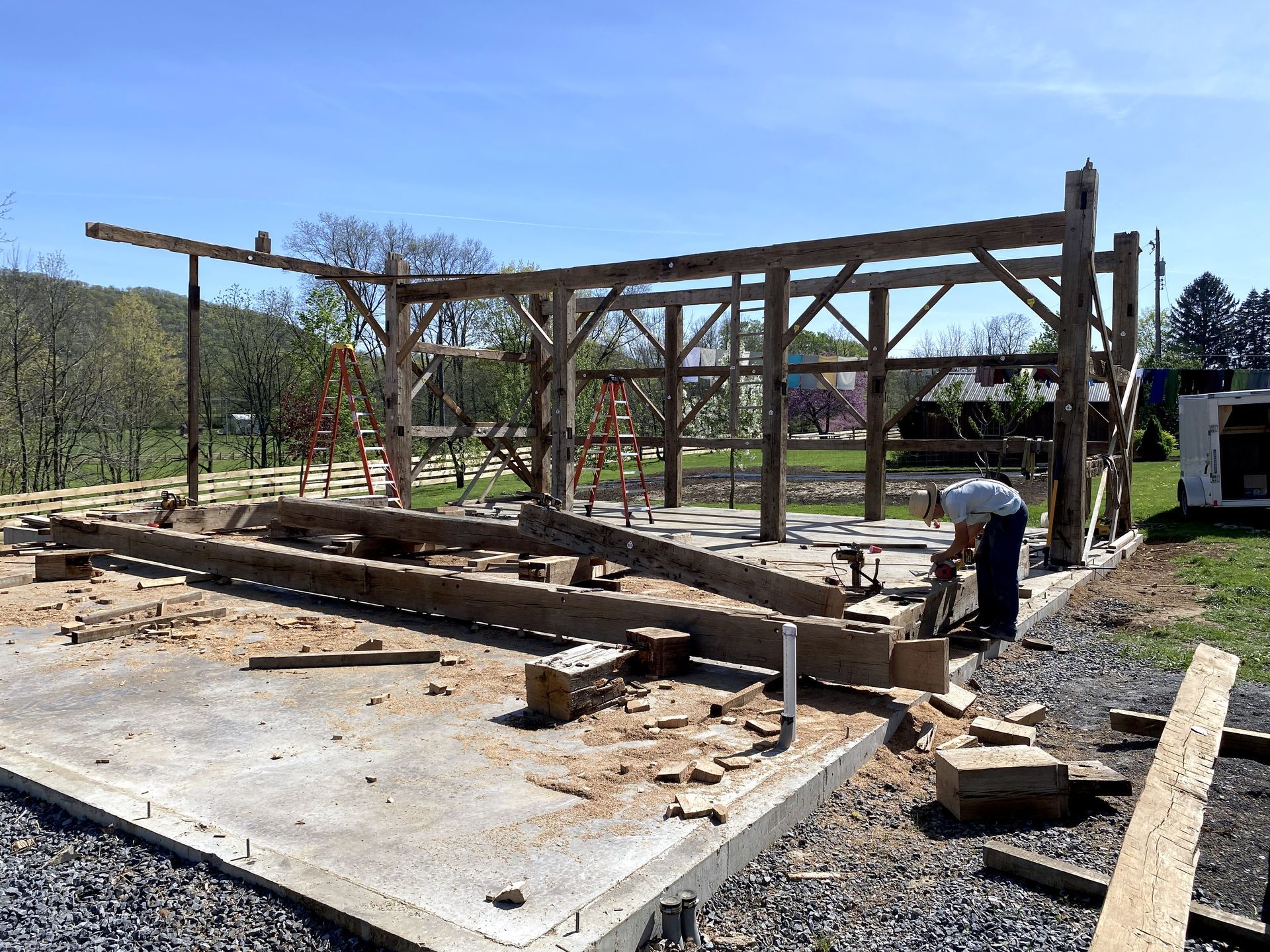 Construction of a wooden barn in Pennsylvania with a worker building the structure on a concrete.
