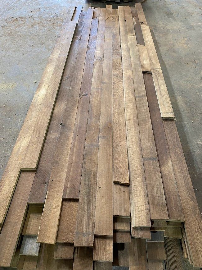 Stack of reclaimed wood planks on a concrete floor for acclimation.