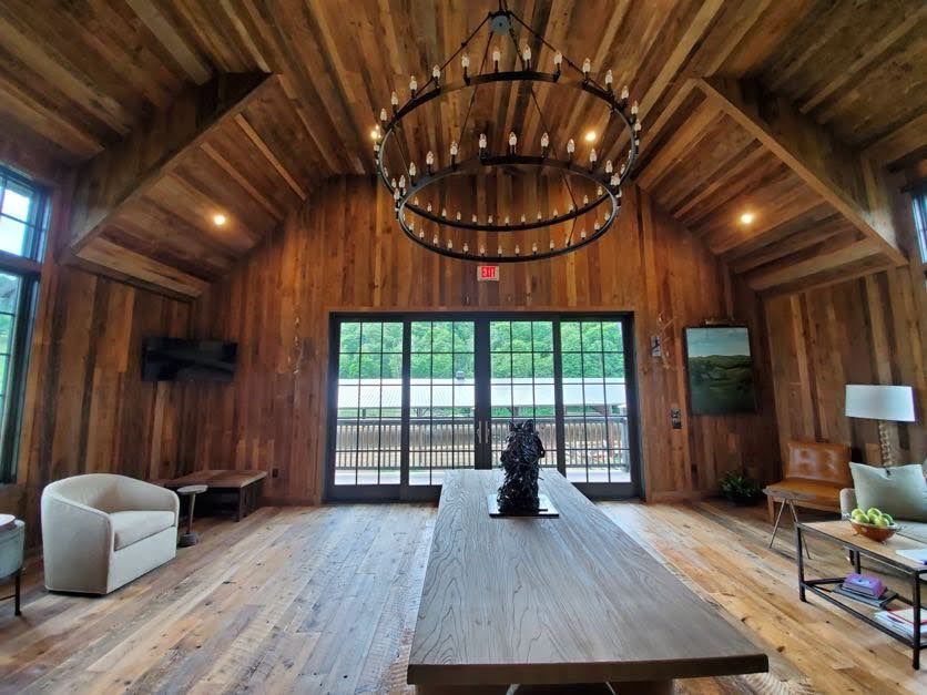Wooden interior in Pennsylvania with chandelier, long table, and windows overlooking porch greenery