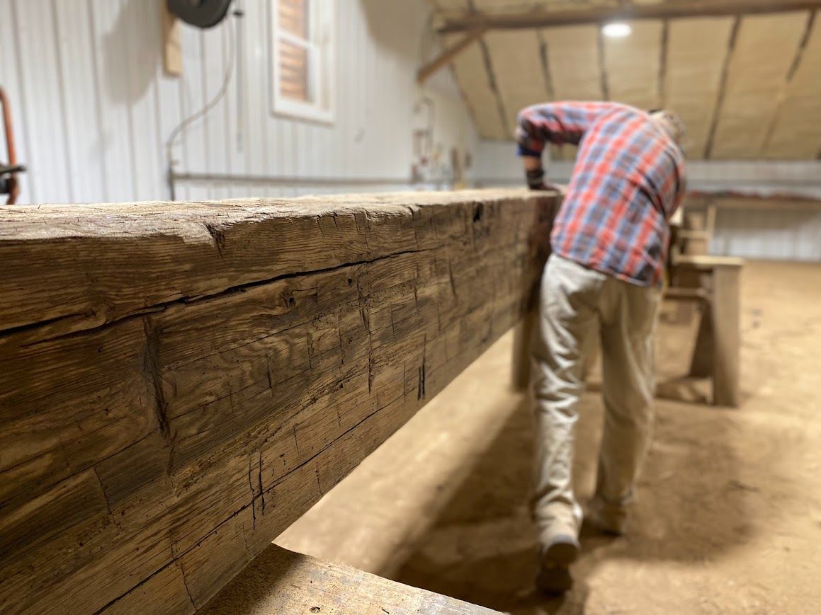 Worker inspecting reclaimed beam for structural integrity.